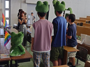ワニ博士のキャップを被って写真を撮られる人たちの後ろ姿の画像